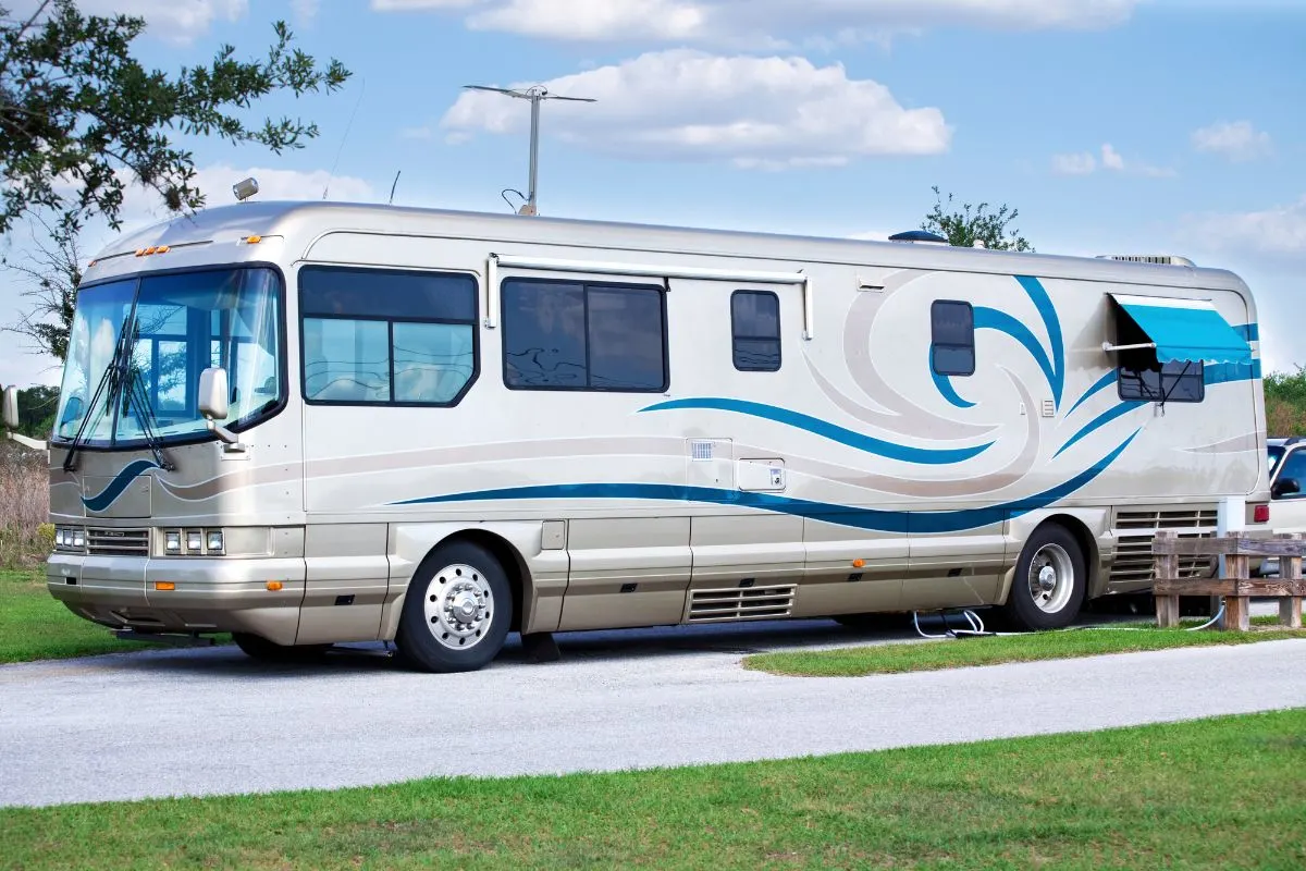 Side view of large Class A Motorhome RV on camp site.