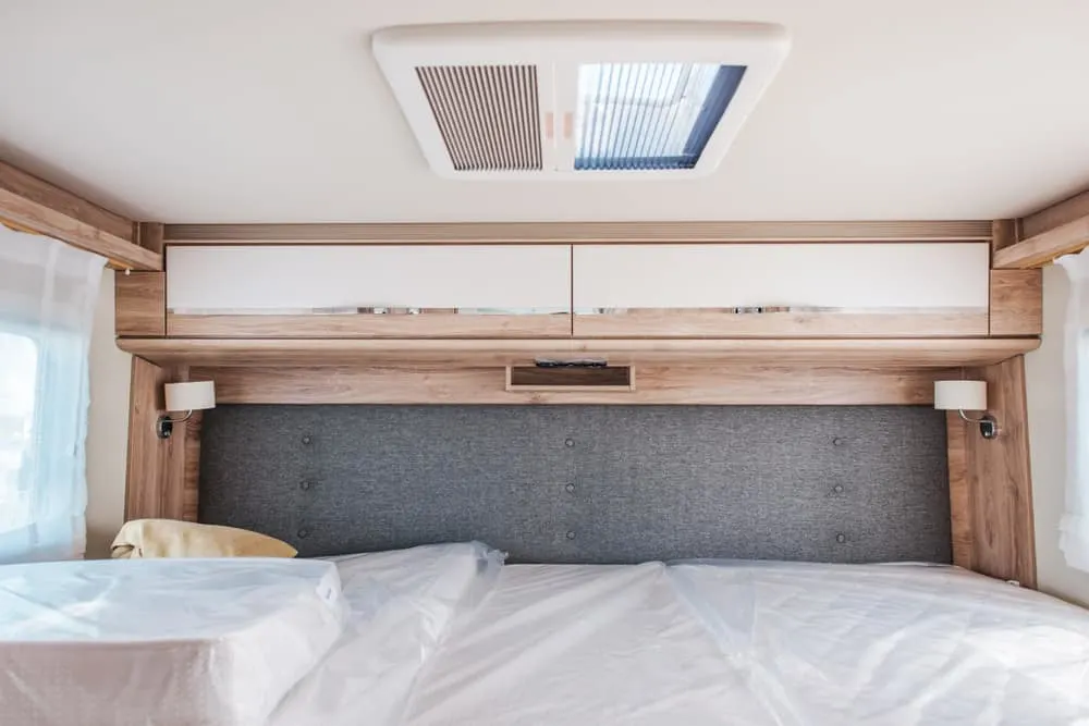 This is a close look at a camper van's bedroom area with a small bed and low head room.