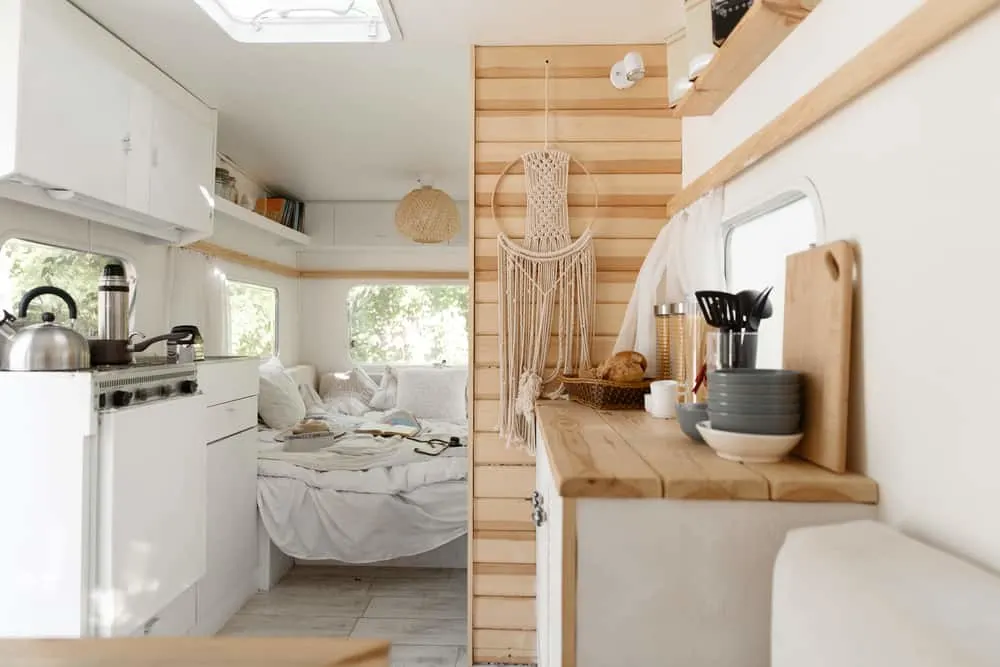 This is a close look at the motor home kitchen with white fixtures and wooden accents.