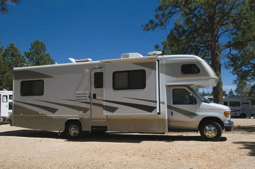 A Class C Motorhome parked near a tree.