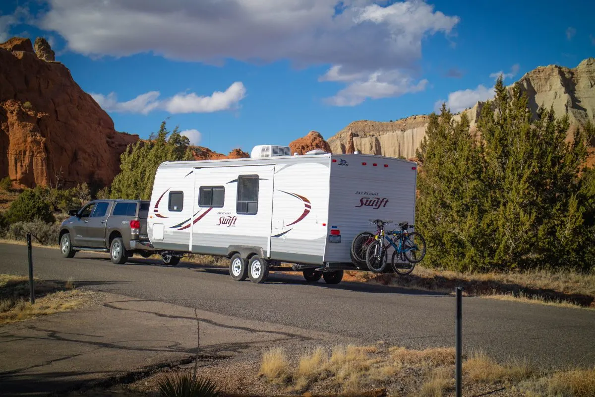 Truck pulling classic travel trailer on road near to mountain hill. 