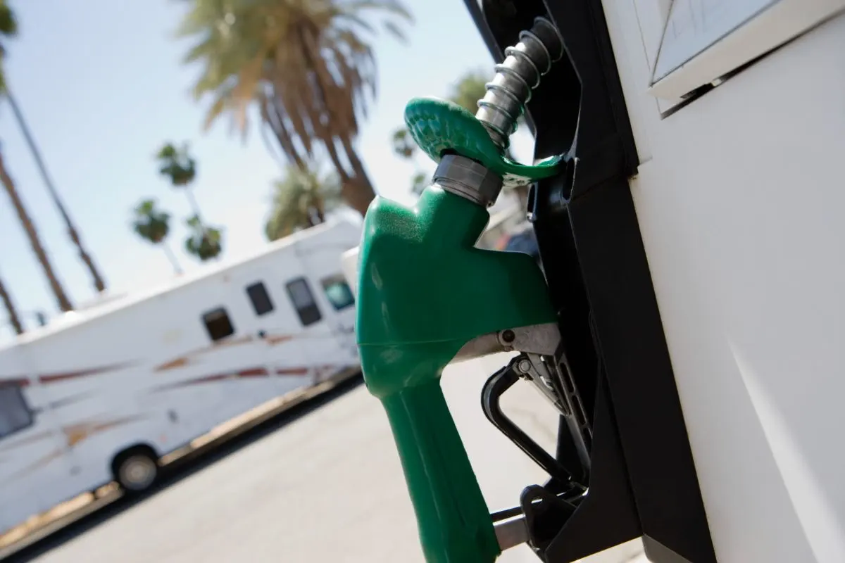 Close up photo of green fuel pump and a RV background.