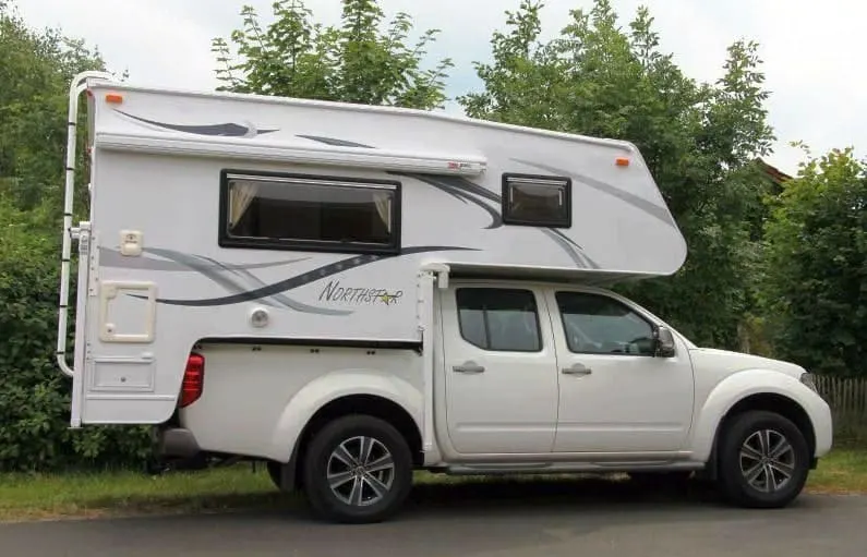 Demountable camper parked on the side of the road.