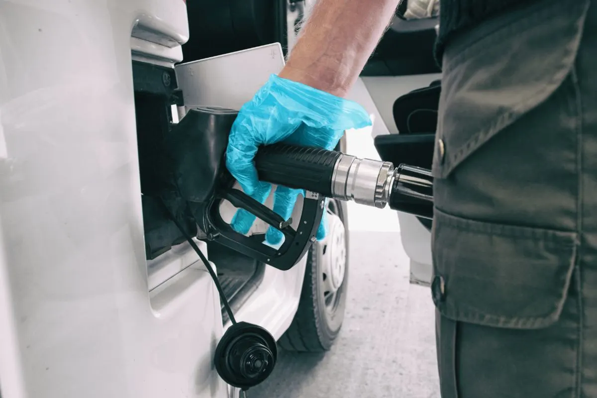 Close up photo of mans hand with gloves pumping gas fuel in rv.