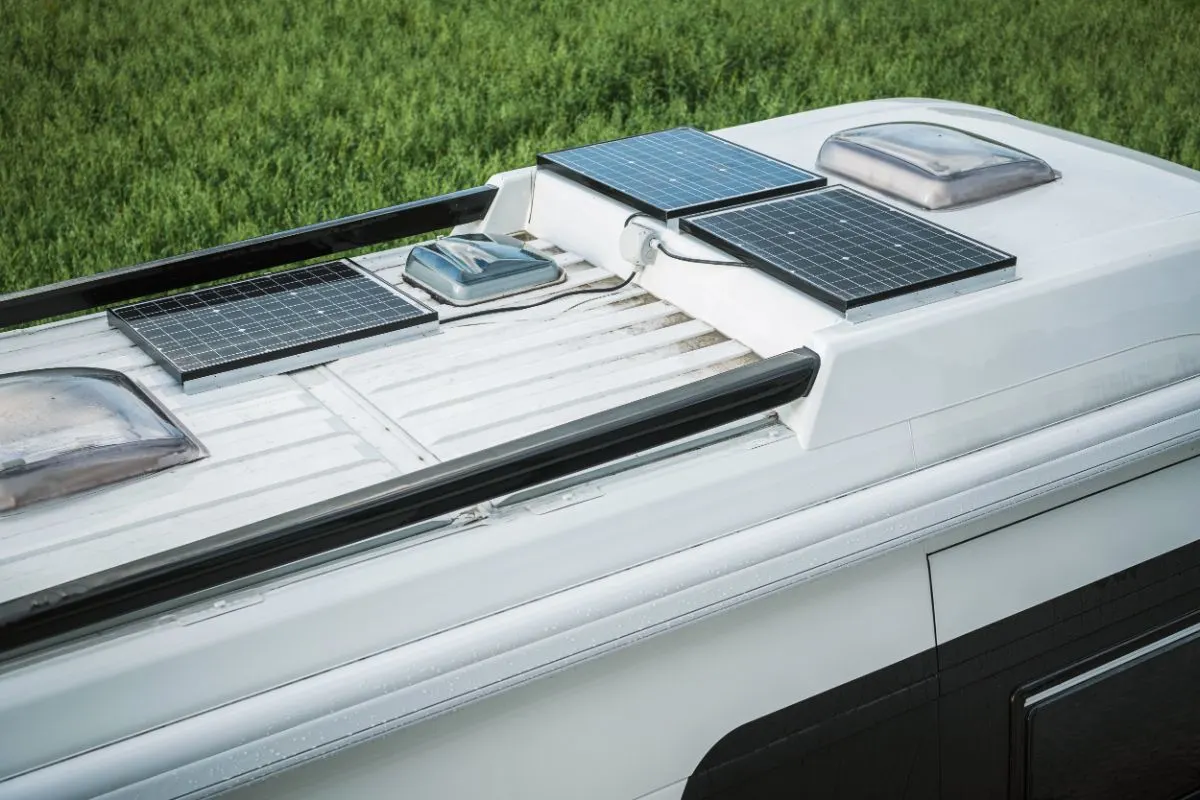 Close up view of parked rv with three solar panels on top of the roof.