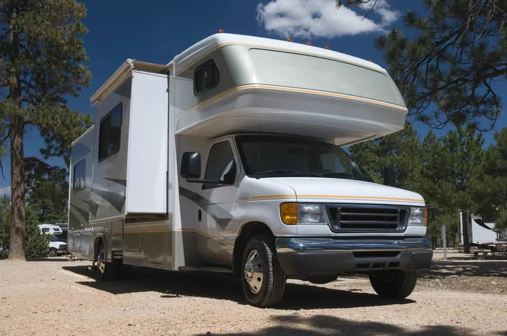 This is a close look at a class C motorhome parked at a camp site.