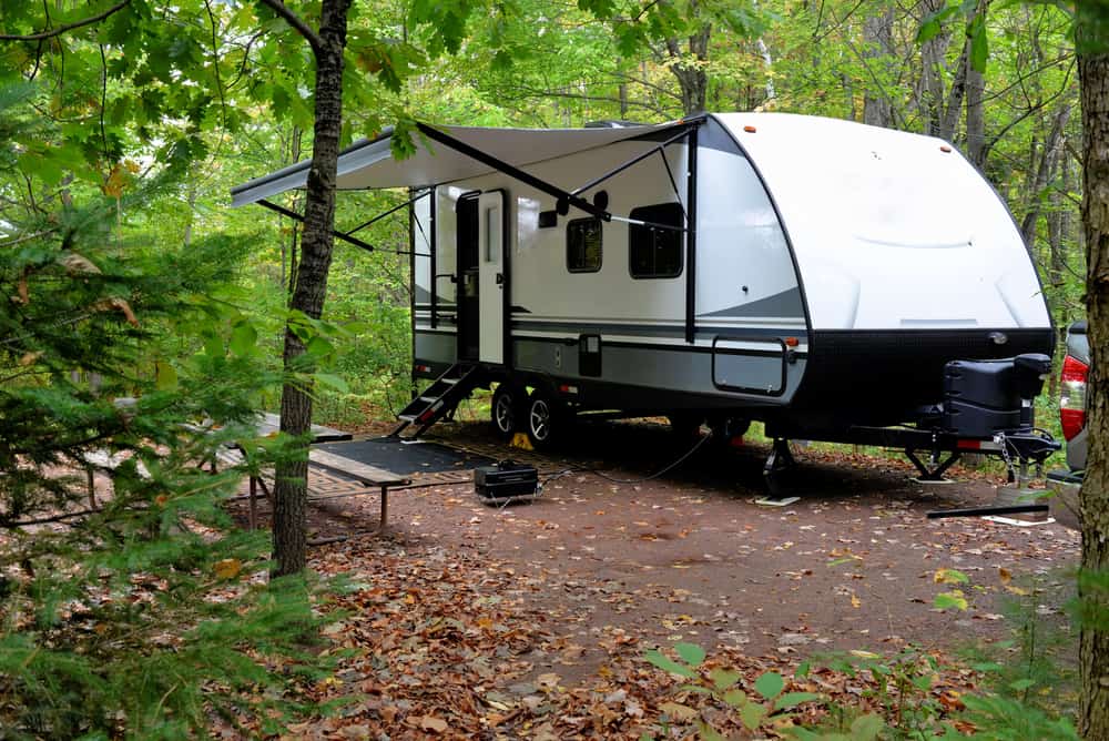 This is a close look at a travel trailer parked at a forest camp site.