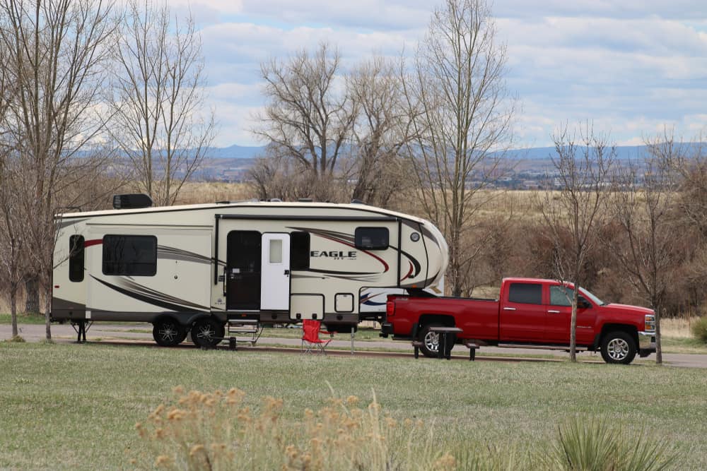 This is a close look at a Fifth-Wheel Camper pulled by a red truck.