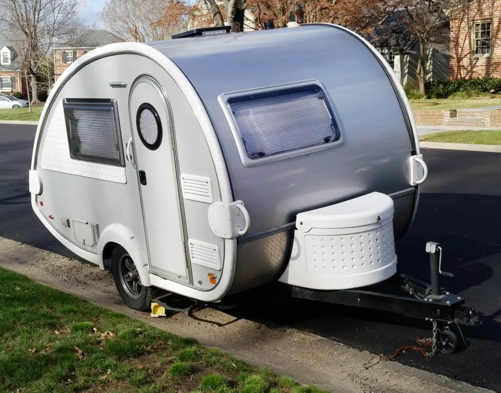 This is a tiny teardrop camper on the side of the road.