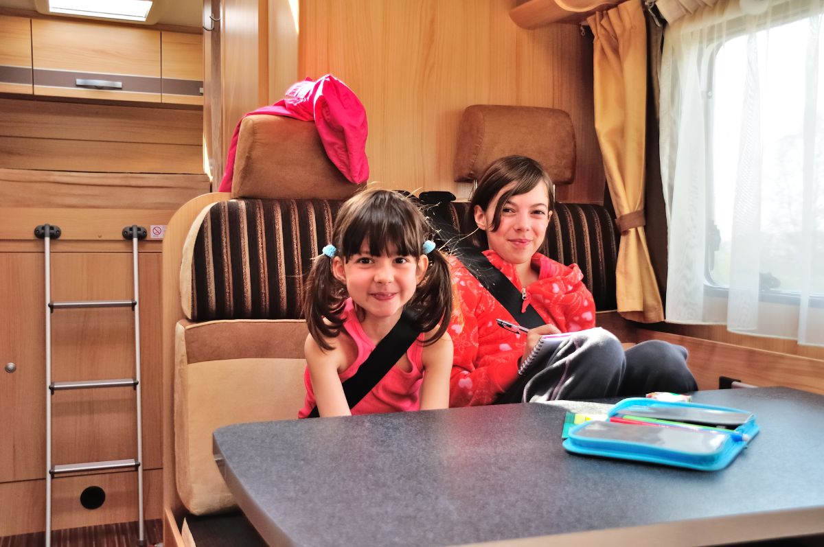 Two kids setting in the RV dining area.