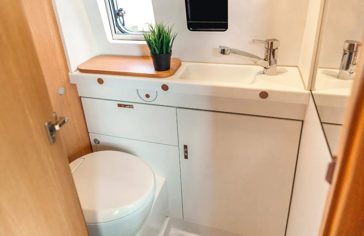 A white painted bathroom storage close to a toilet.