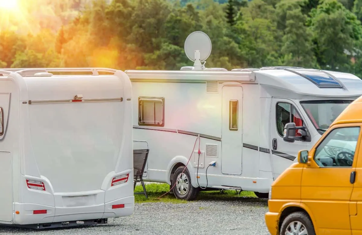 RVs parked outdoors with one RV featuring an installed satellite.