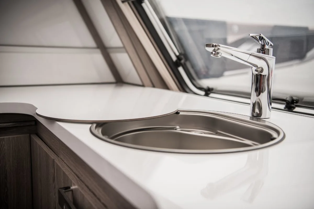 A circular RV sink with cover and faucet.