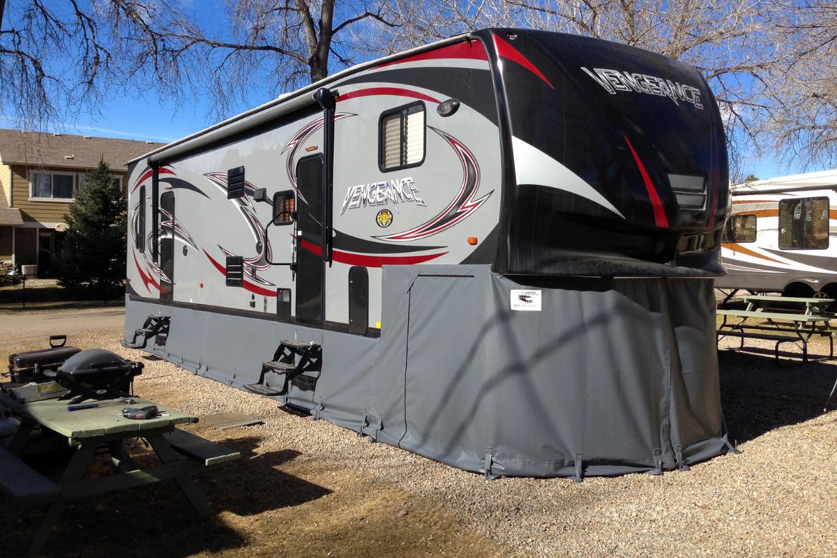 A big RV or recreational van parked with an RV skirt for maintaining the RV's function.