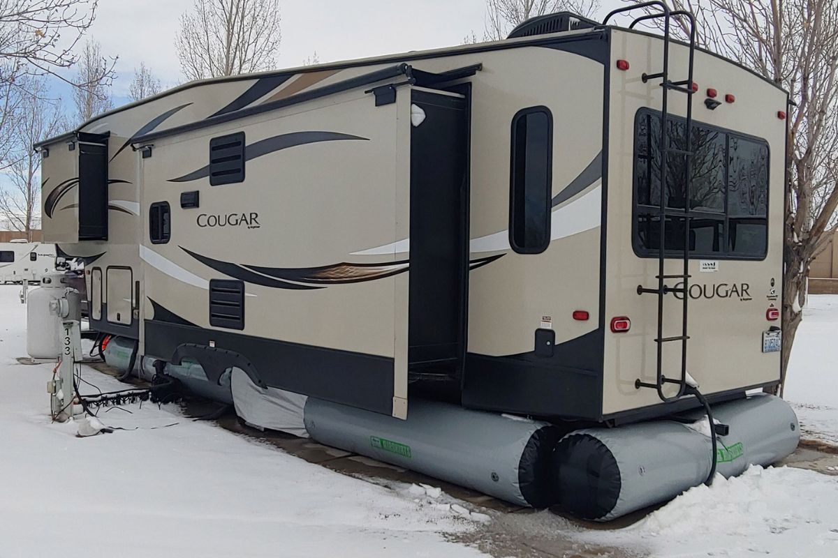 A RV or recreational van parked during winter with RV skirts to protect the van from the winter.