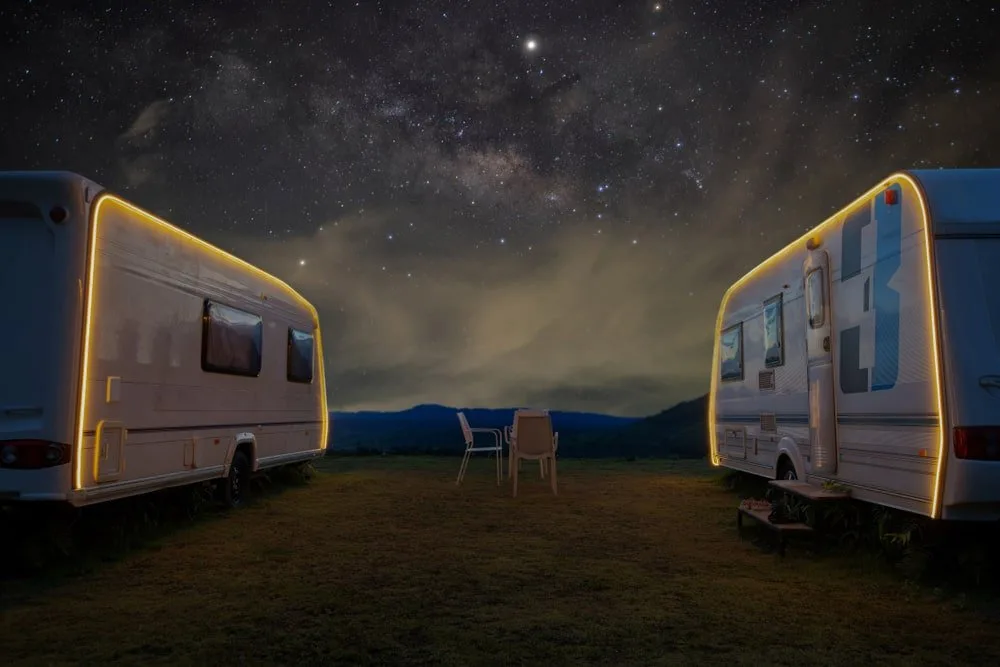 A close look at a couple of travel trailers parked at night.