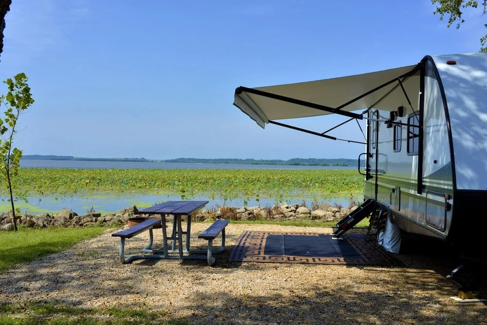 A close look at a travel trailer parked on the side of a river.