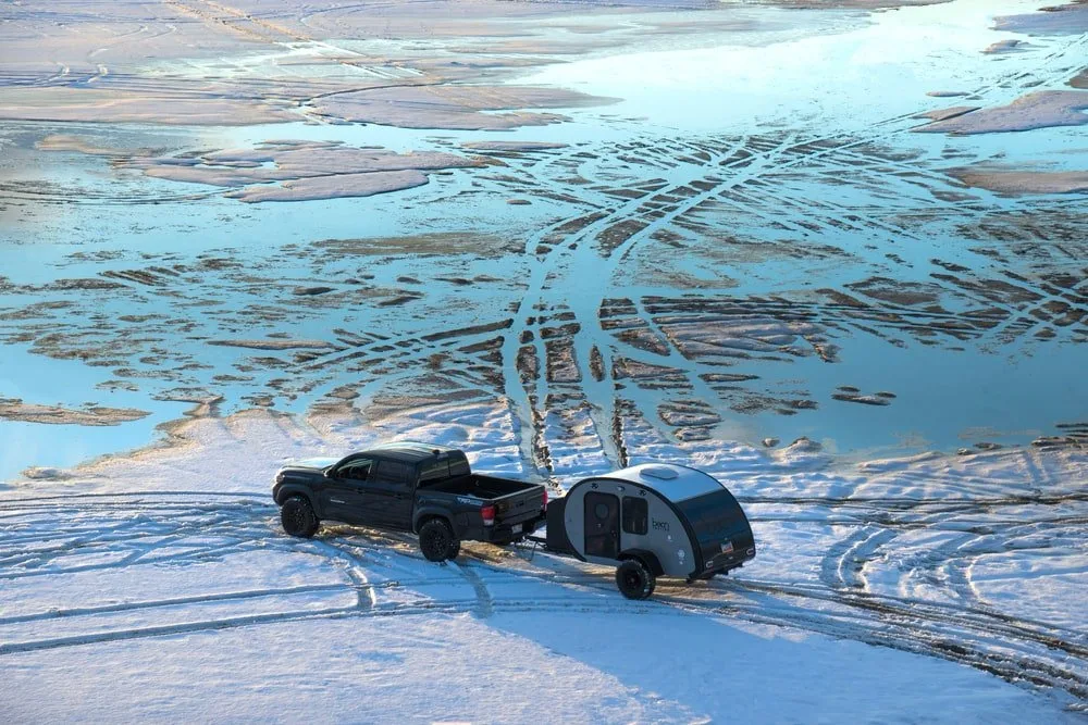 An aerial view of a black truck pulling a teardrop trailer.