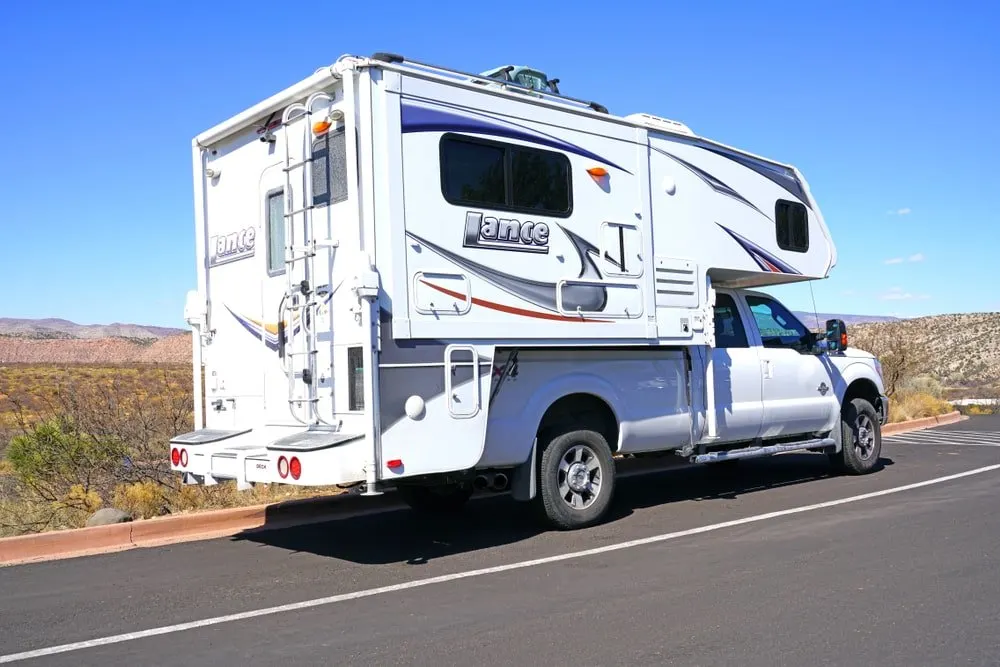 A white truck camper on the road.