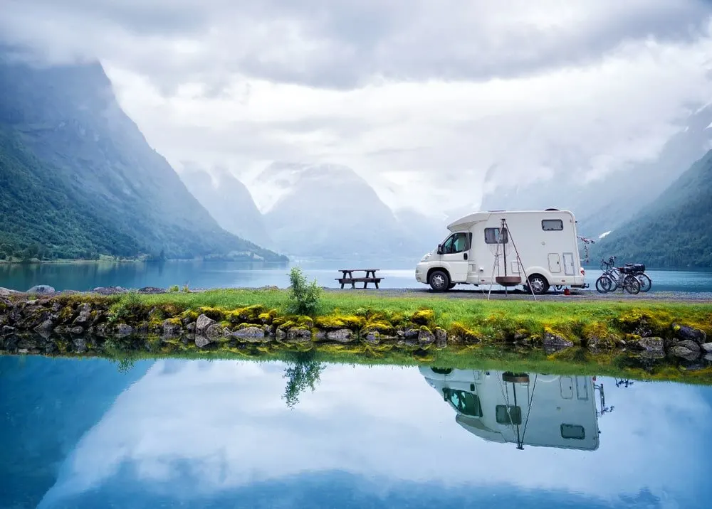 A small RV parked at a campground surrounded by water.