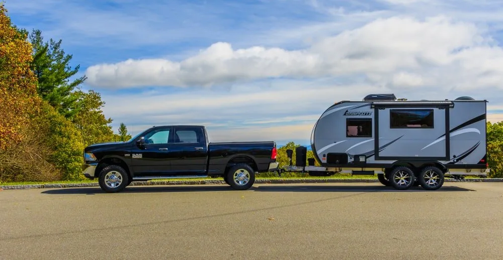 A truck pulling a camp trailer on the road to the camp site.