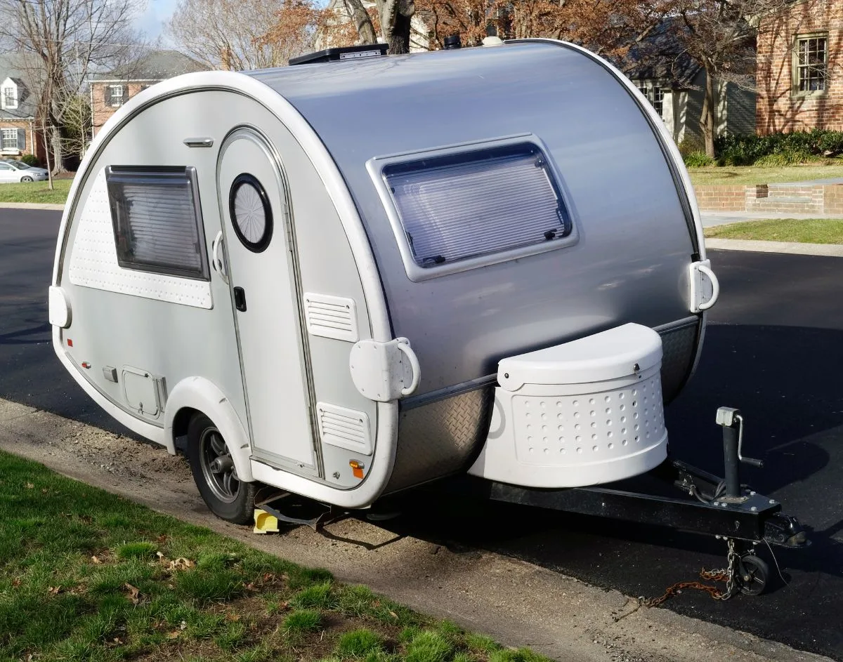 A teardrop trailer standby on street side walk.