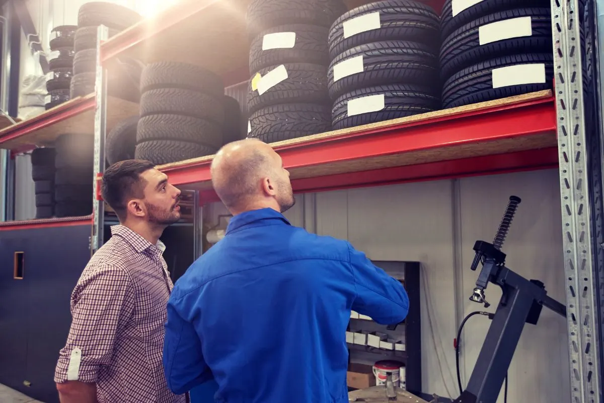 Two man talking about the tires in a car shop.