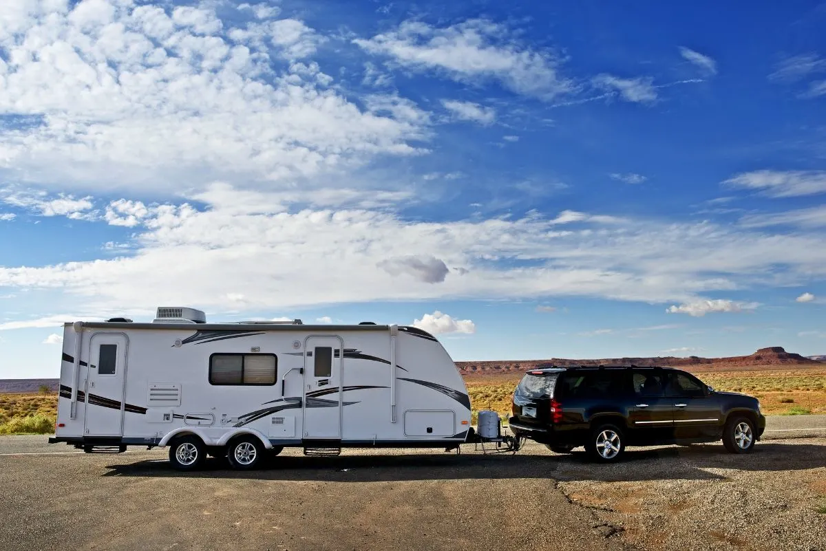 An SUV towing a travel trailer on road.