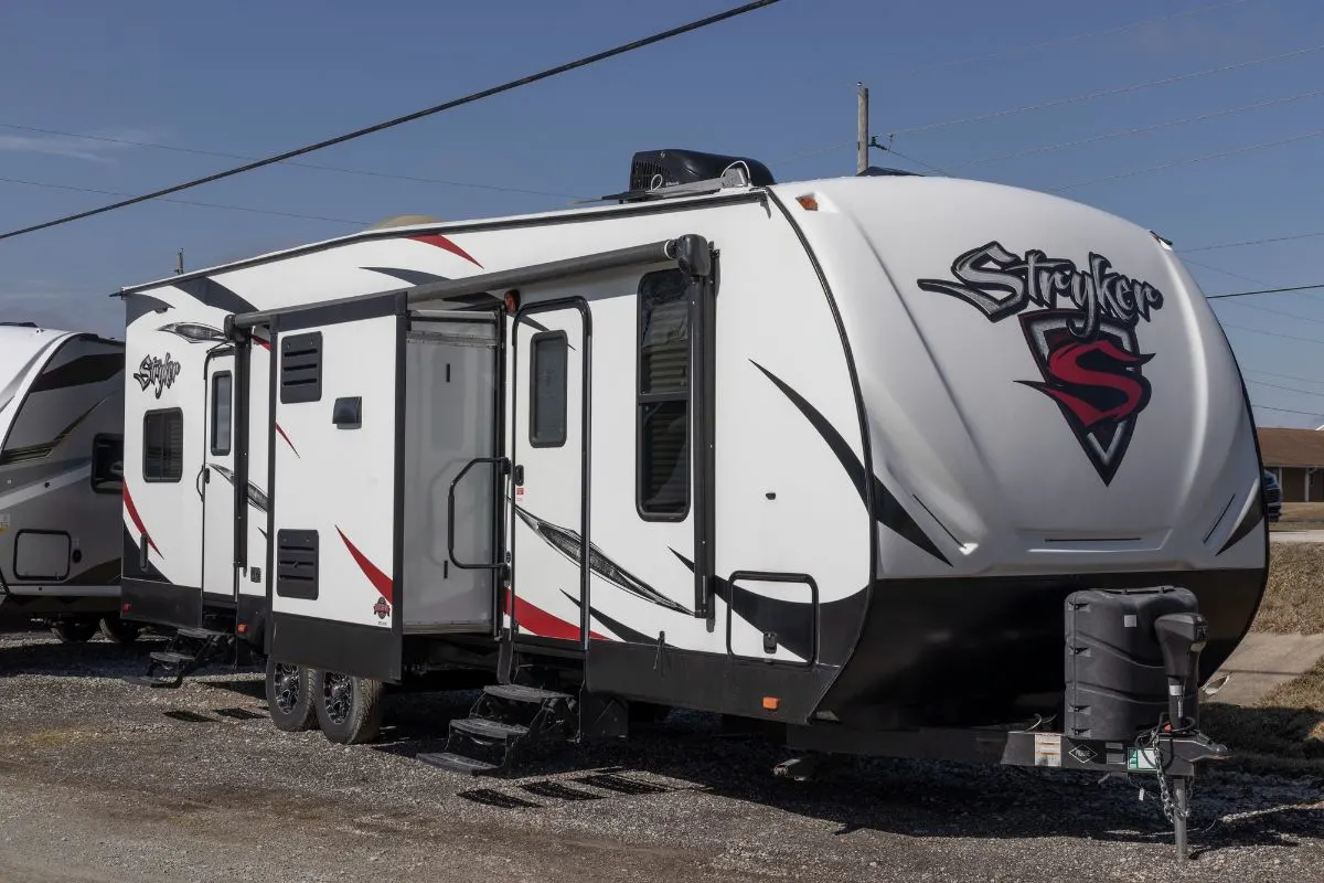 A travel trailer toy hauler standby in an open space area.