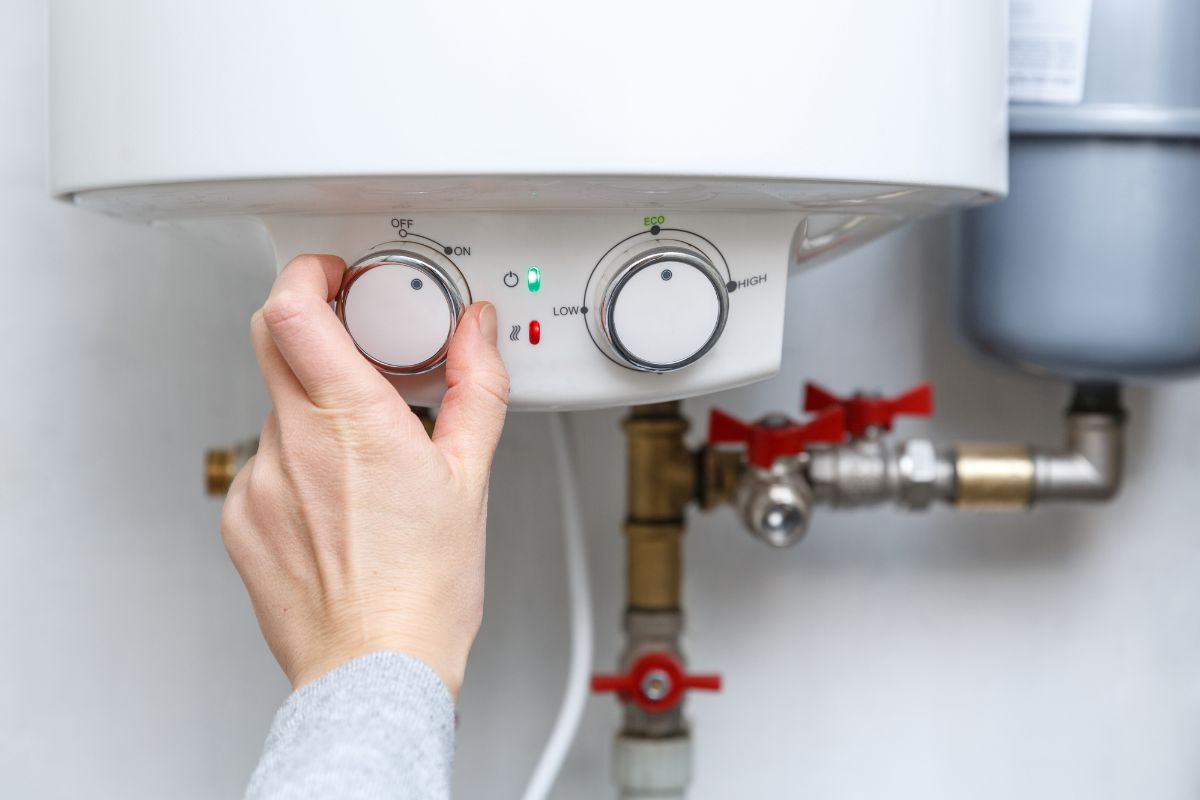 A hand turning on a water heater.