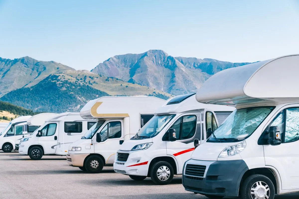 Different types of RVs in a row close to mountains.