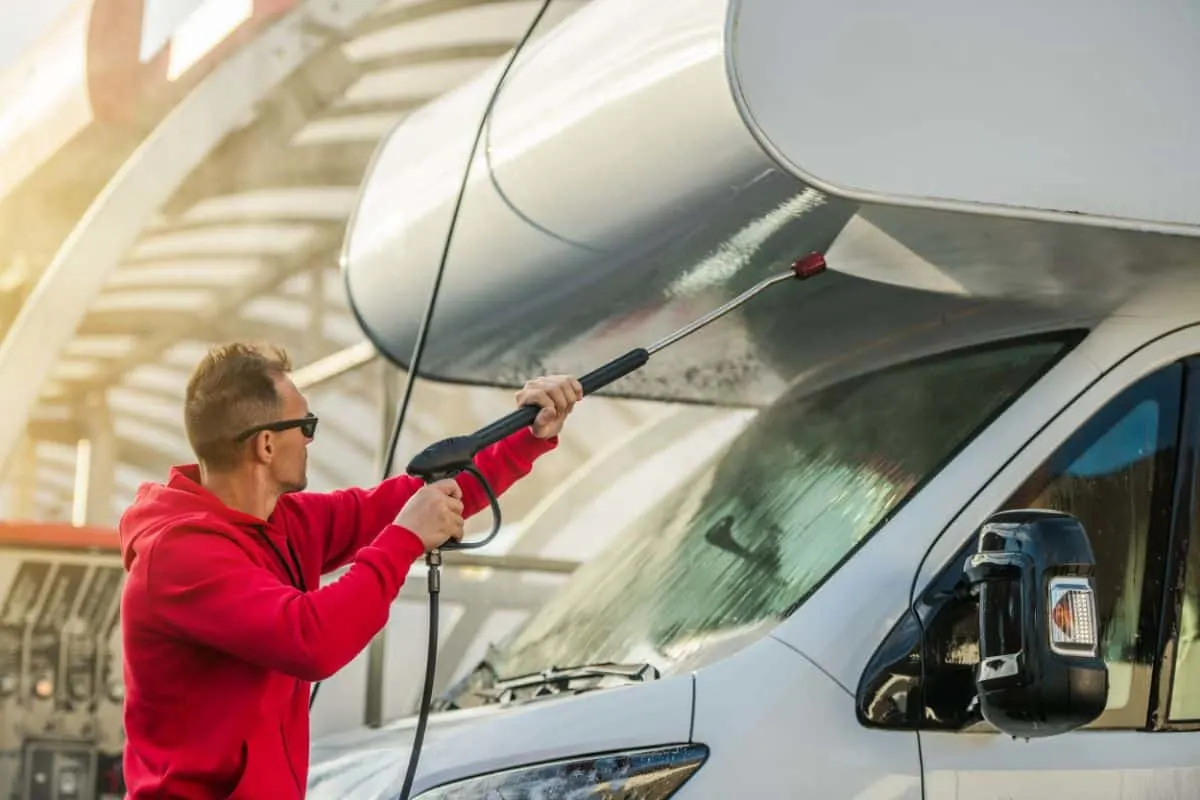 A man uses pressure washer to clean an RV.