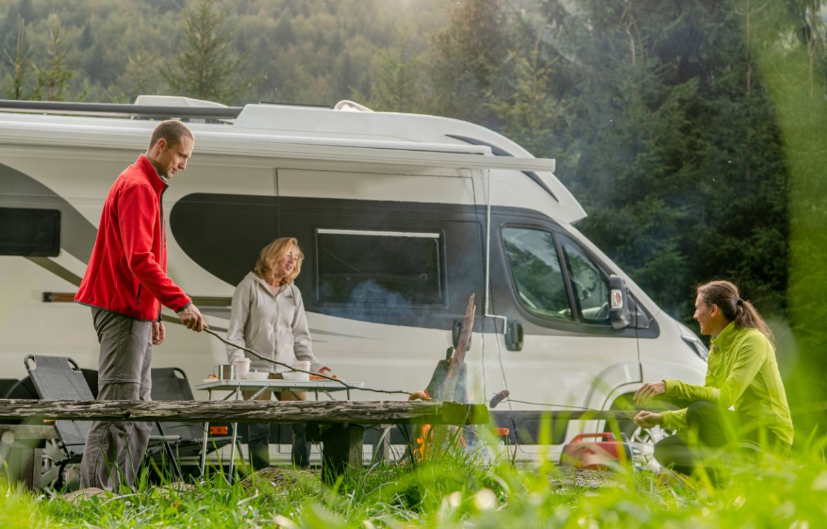 A family cooking outside a class b camper.