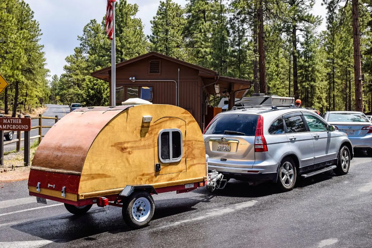 An SUV towed a teardrop camper on road.