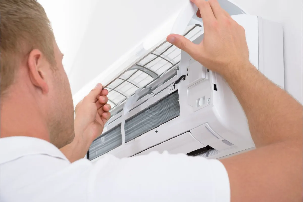 A photo of a man in white shirt inspecting the air condition.