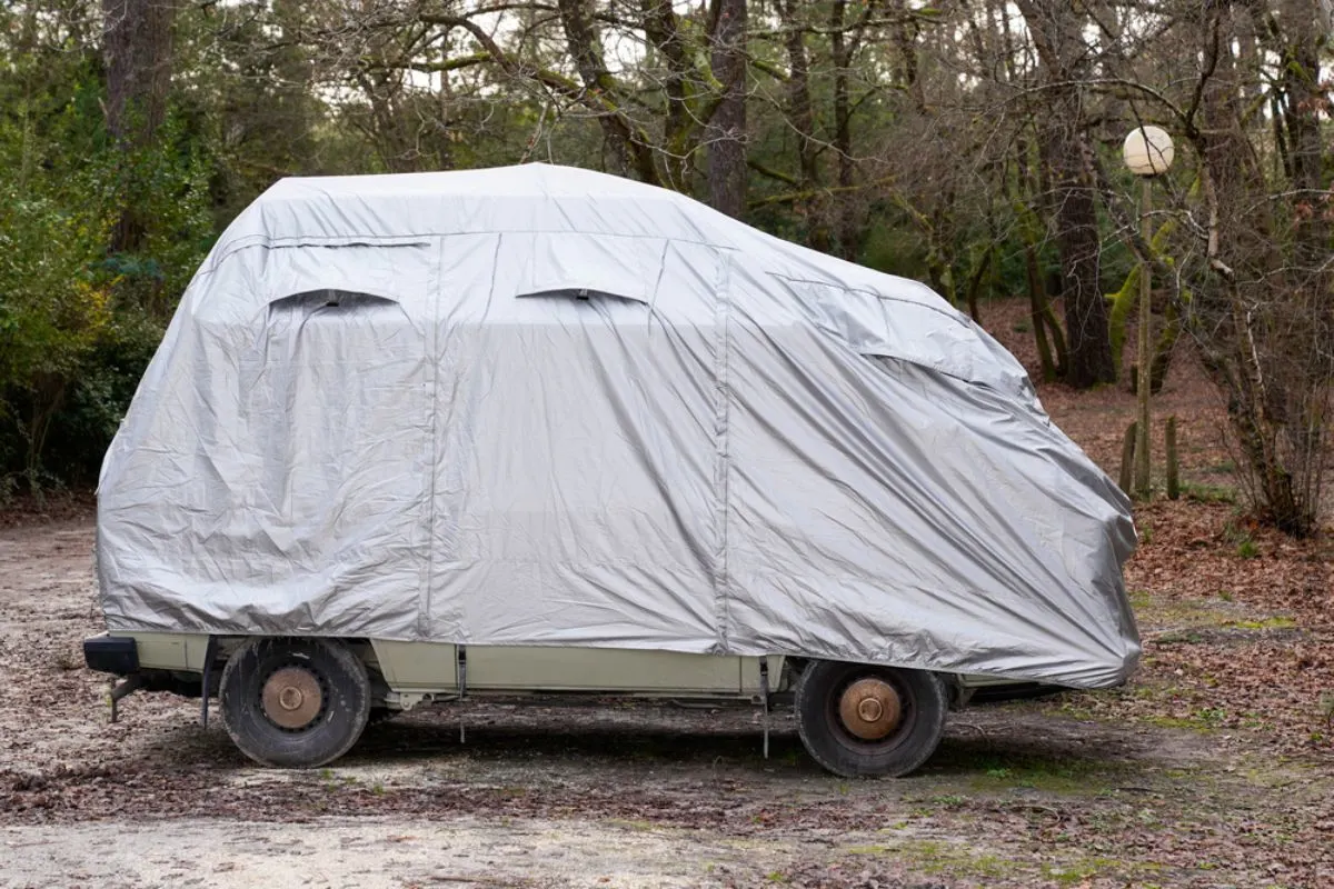 A camper van parked in the forest with covered with RV protection.