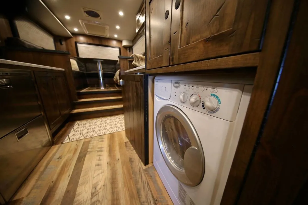 A luxurious RV interior with brown theme room with washer and dryer combo.