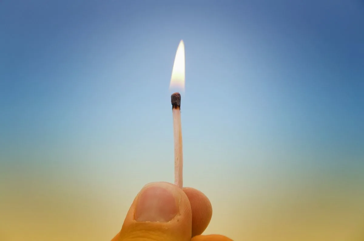 A hand holding a lighted match.