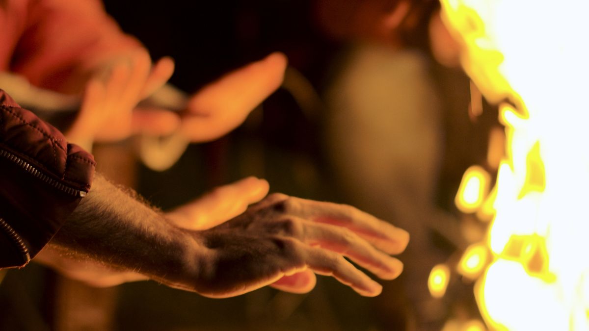 Hands warming at the fire.