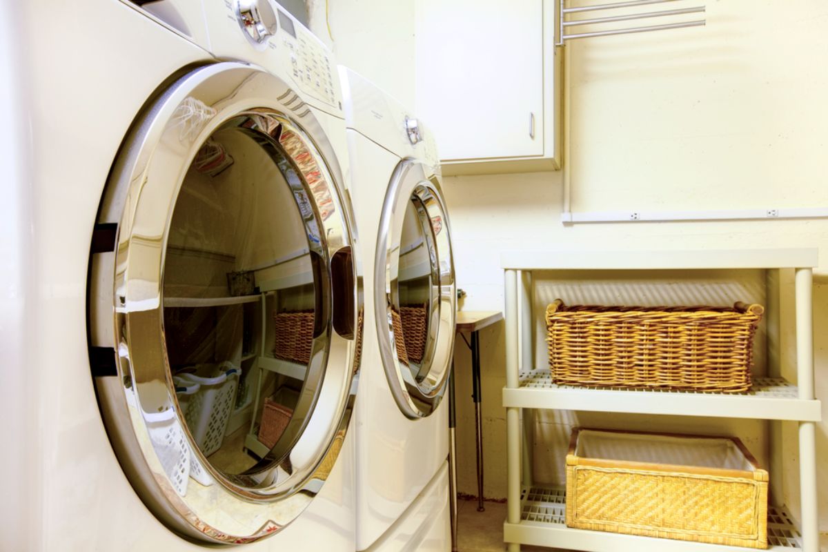 A washer and dryer in a small space laundry room with two brown baskets.