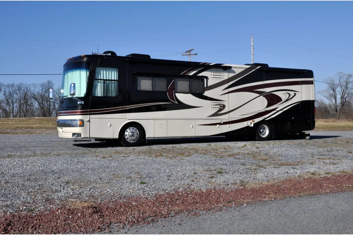 A black and white recreational vehicle with mini-bus size parked outisde in the sunny day.