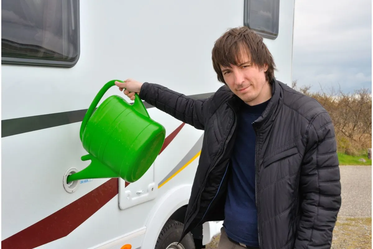 An traveler adult man refilling the water tank of his RV.