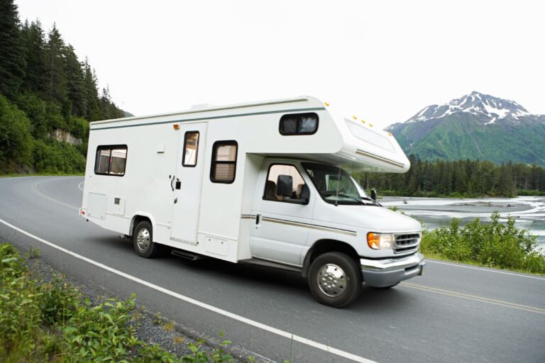 A white RV or recreational van being photographed in the highway.