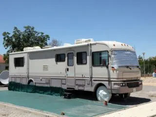 A large bus size RV parked at a camping site with it's designated parking area for vehicles.