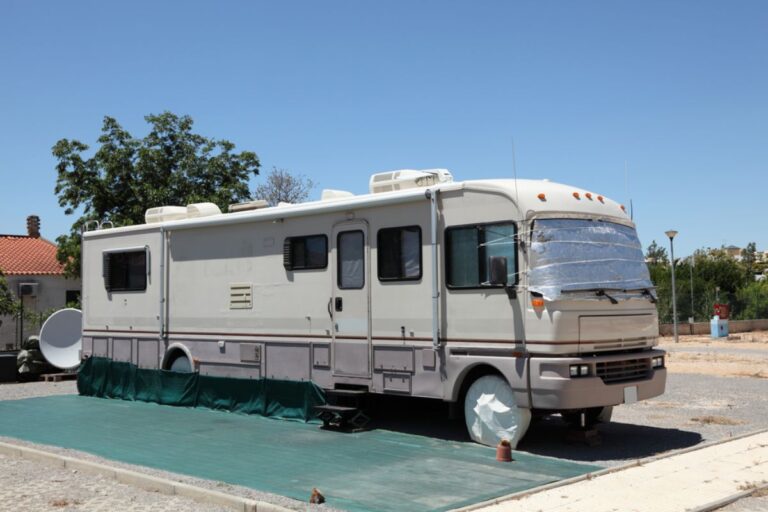 A large bus size RV parked at a camping site with it's designated parking area for vehicles.