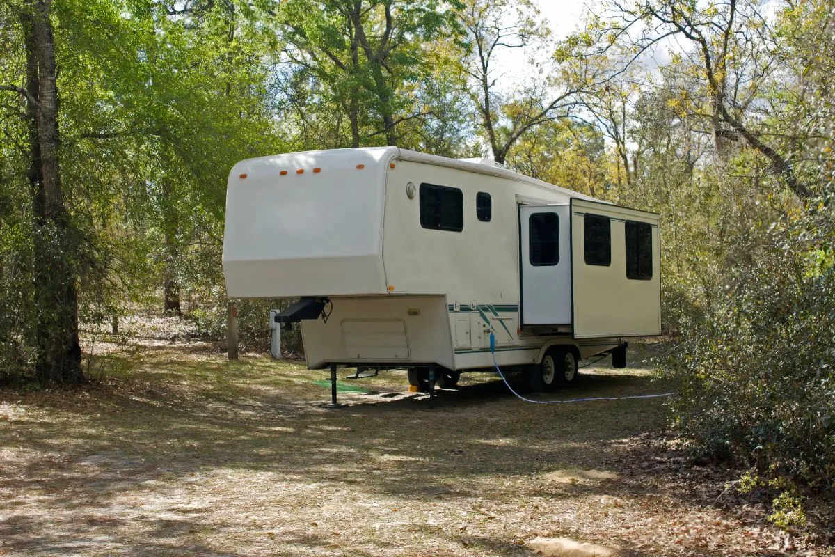 A trailer RV in camp site with extended slide-out.