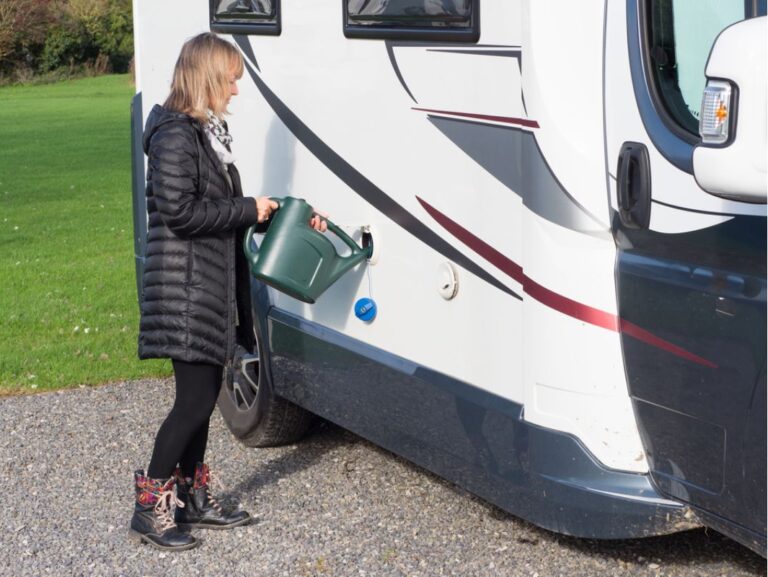 A woman refilling the RV water tank for their convinience with a full galloon.