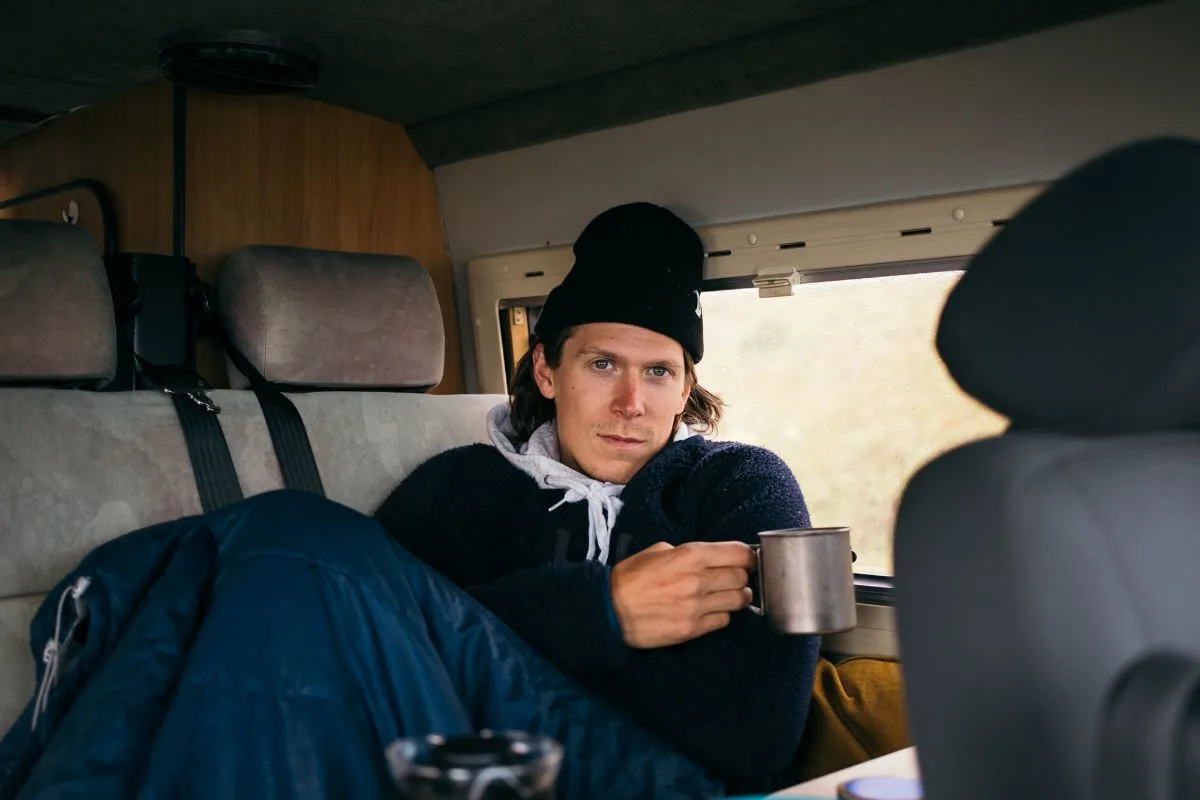 A man feeling too cold with a mug of coffee inside the RV.