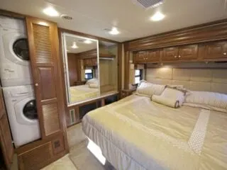 A luxurious RV room with with king size bed and washer and dryer combo.