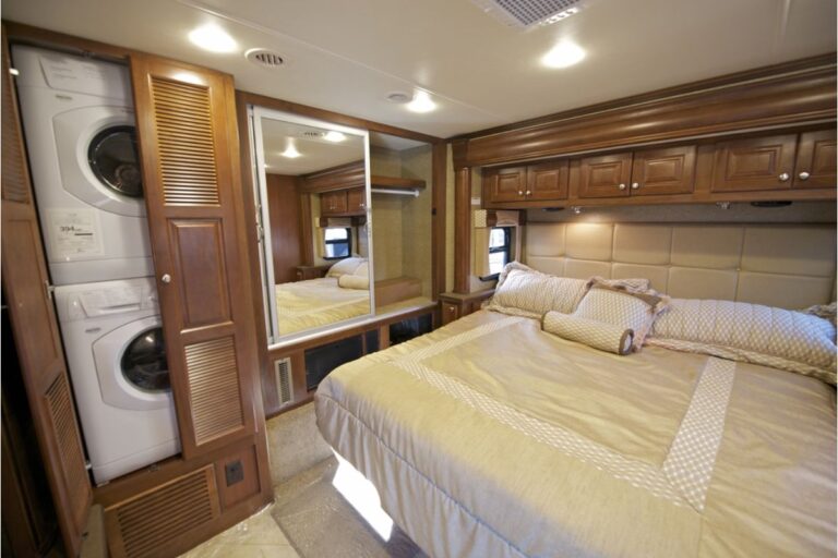 A luxurious RV room with with king size bed and washer and dryer combo.